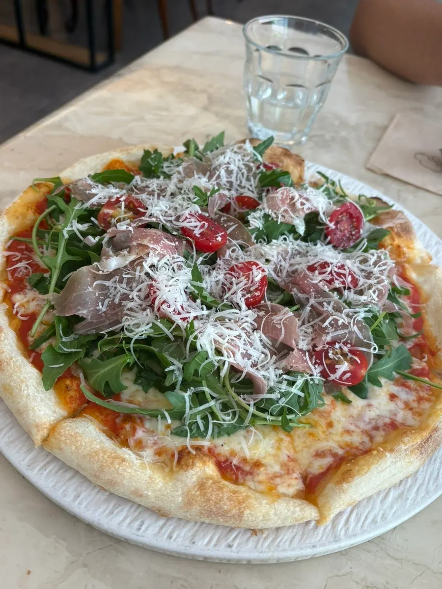 Pizza topped with rucola and prosciutto