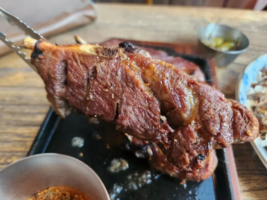 Lamb shoulder rack before being cut with tongs and scissors