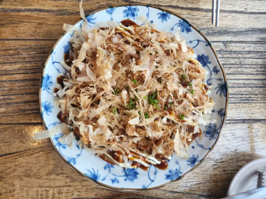 Seafood okonomiyaki topped with sauce and bonito flakes