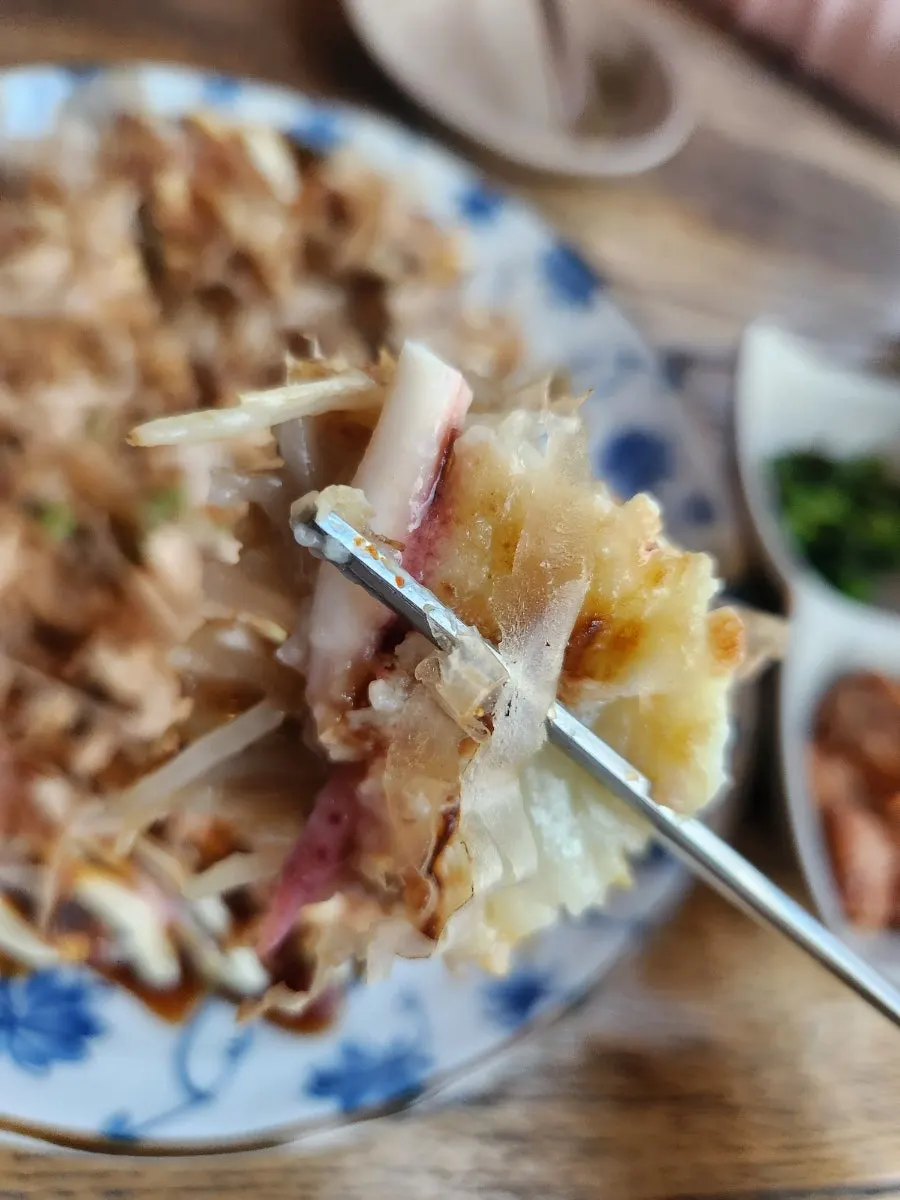A piece of seafood okonomiyaki lifted from the plate