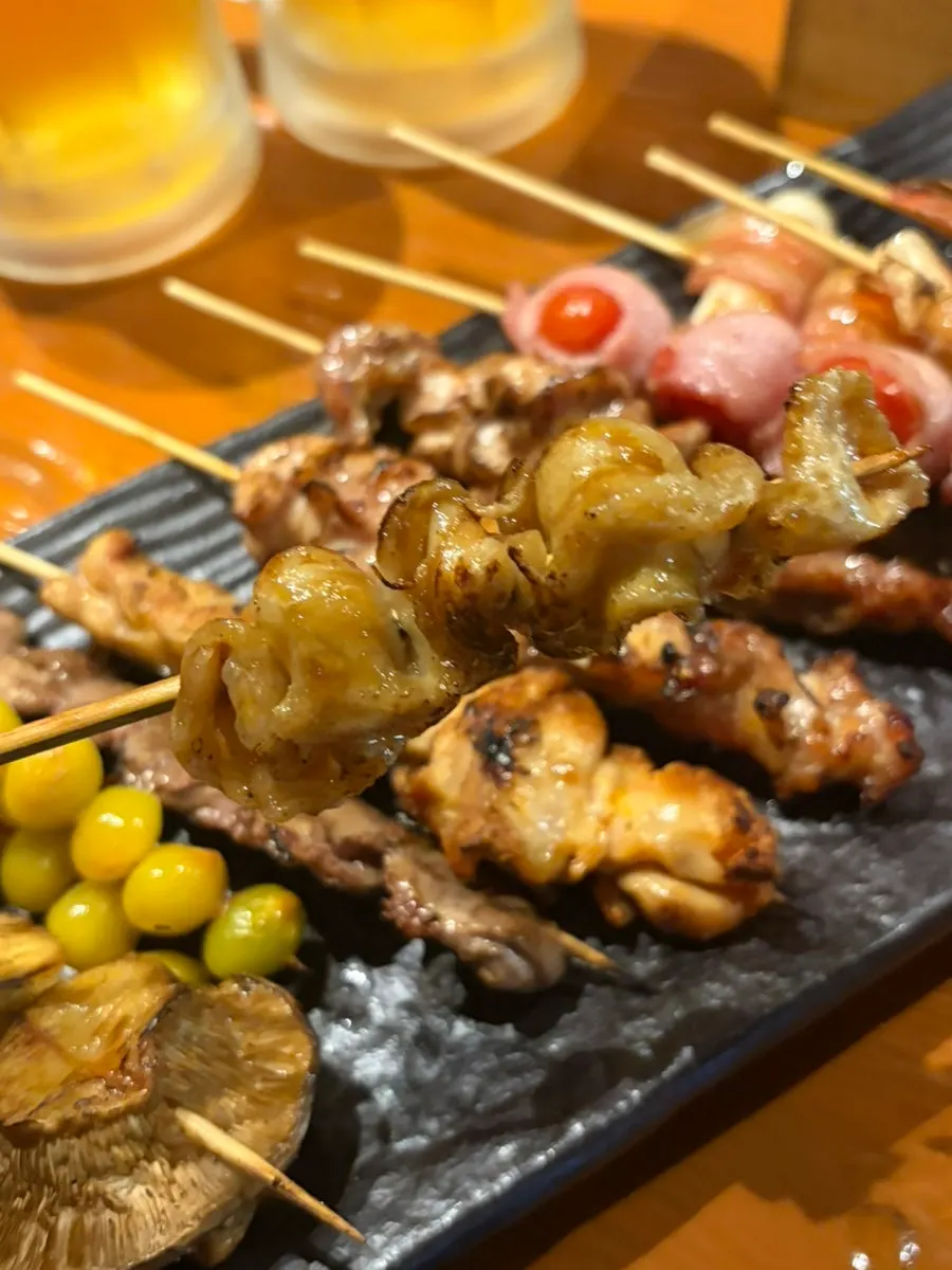 Nearly empty skewer plate next to a draft beer