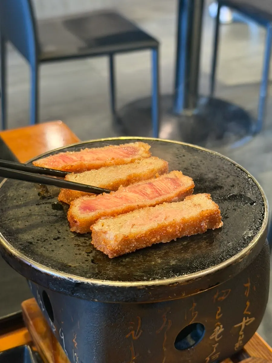 A piece of gyukatsu placed on the mini charcoal grill