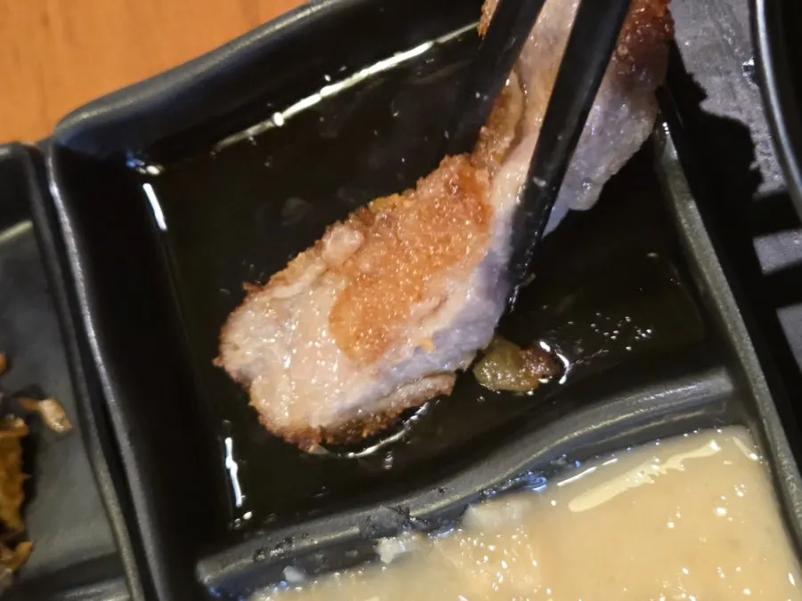 A piece of gyukatsu dipped in soy sauce