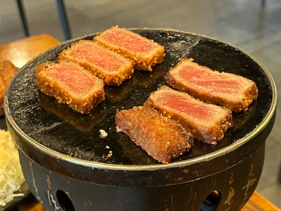 Gyukatsu being grilled on a mini charcoal grill