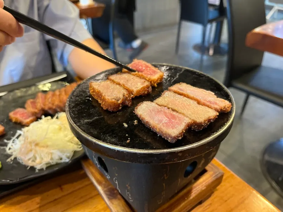 A piece of gyukatsu being grilled on the charcoal grill