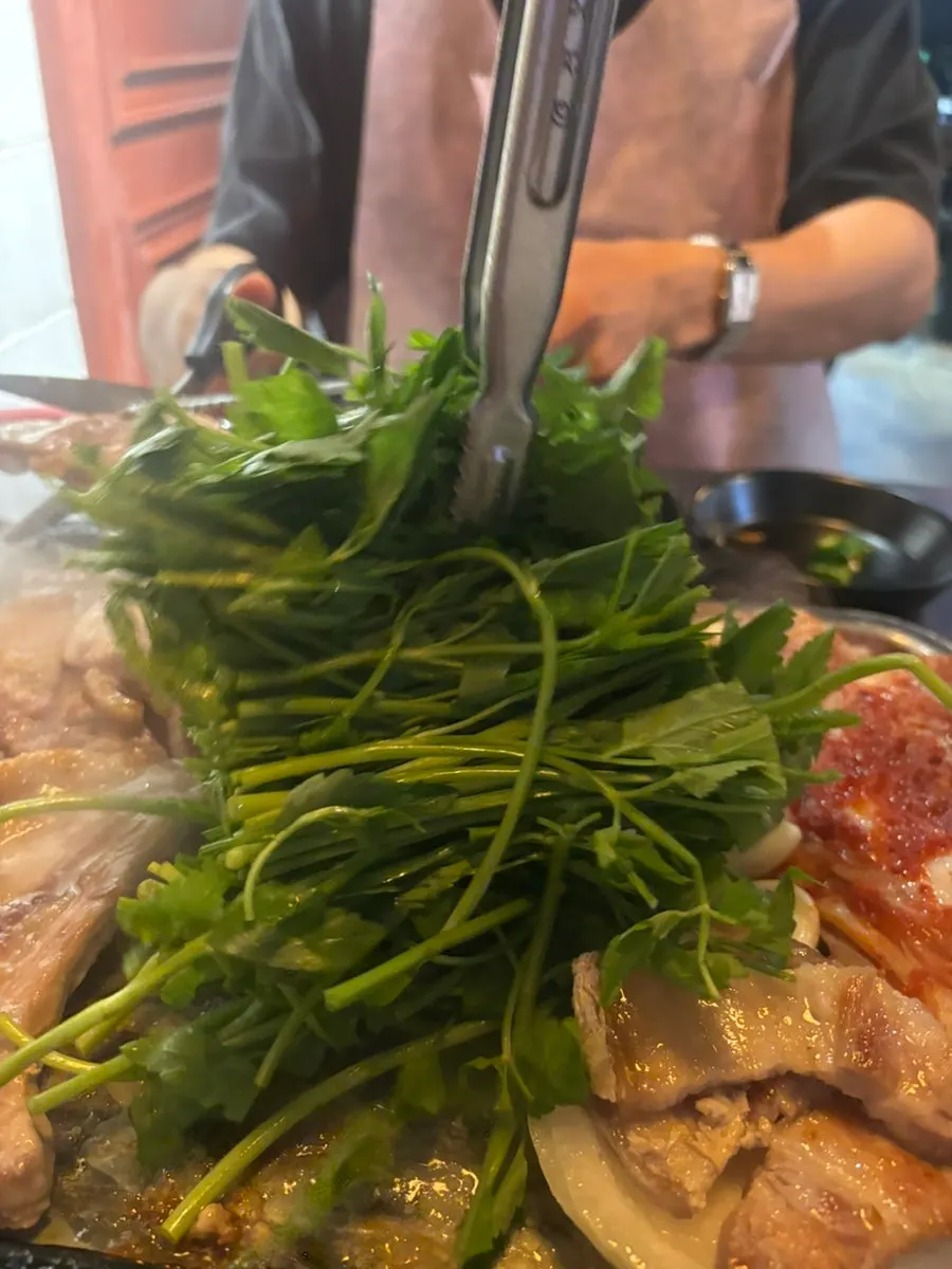 A piece of pork belly wrapped in sautéed minari