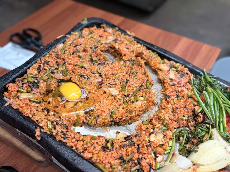 A plate of kimchi fried rice with a smiley face drawn on it