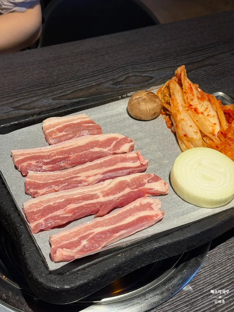 Grill piled high with minari on top of the pork belly