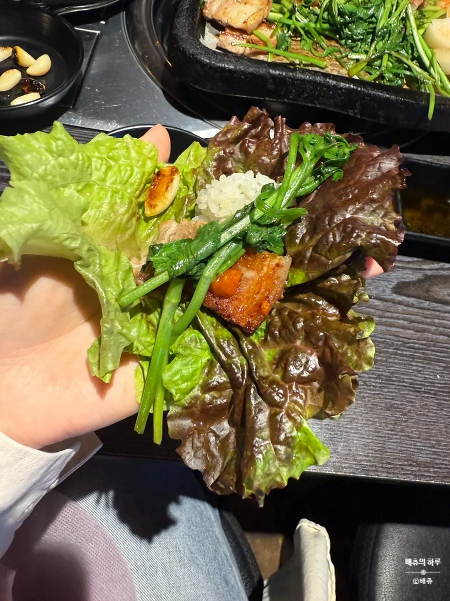 Lettuce wrap piled with pork belly, kimchi, and minari