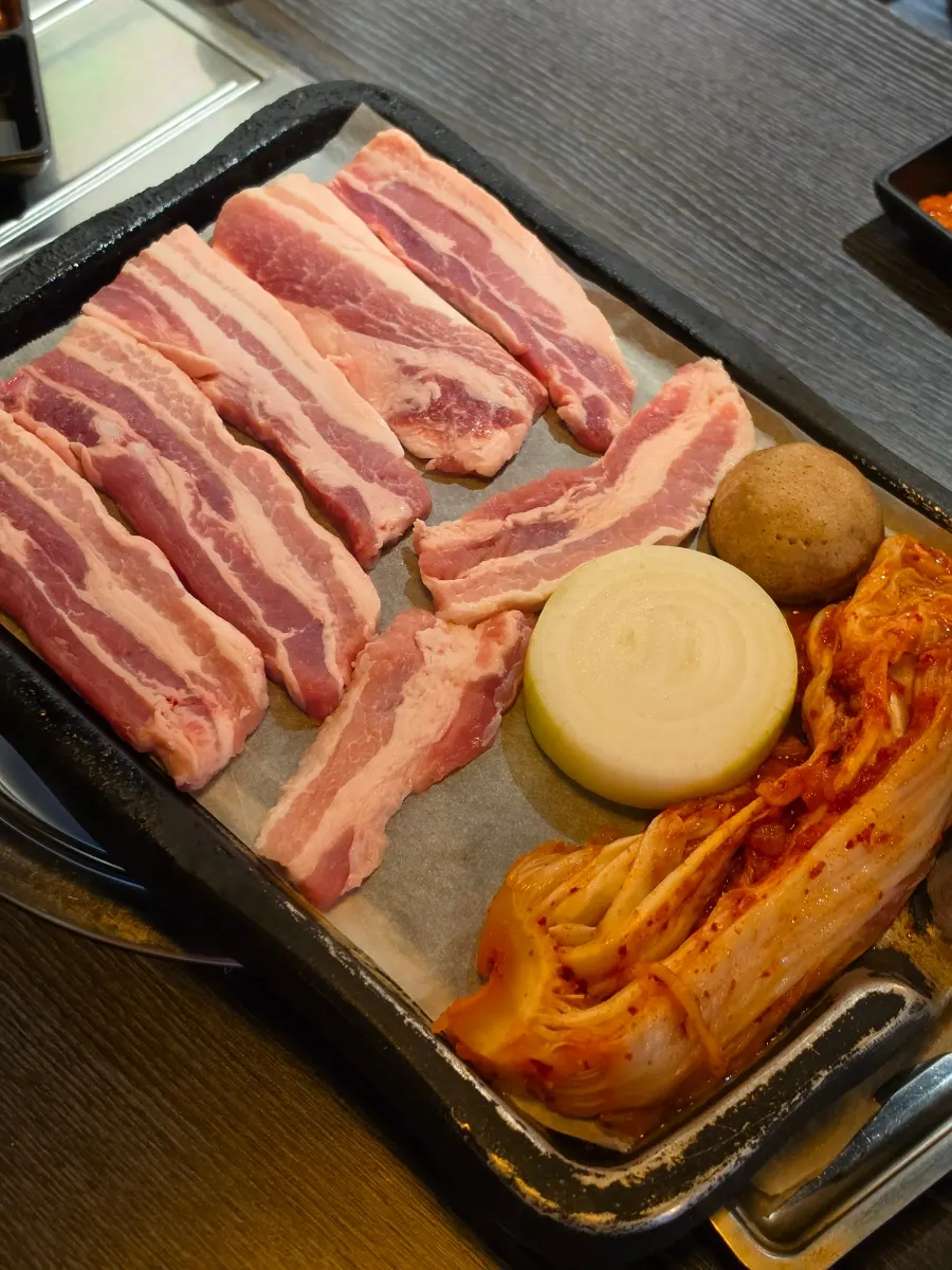 불판에 올린 삼겹살과 포기김치, 양파, 버섯