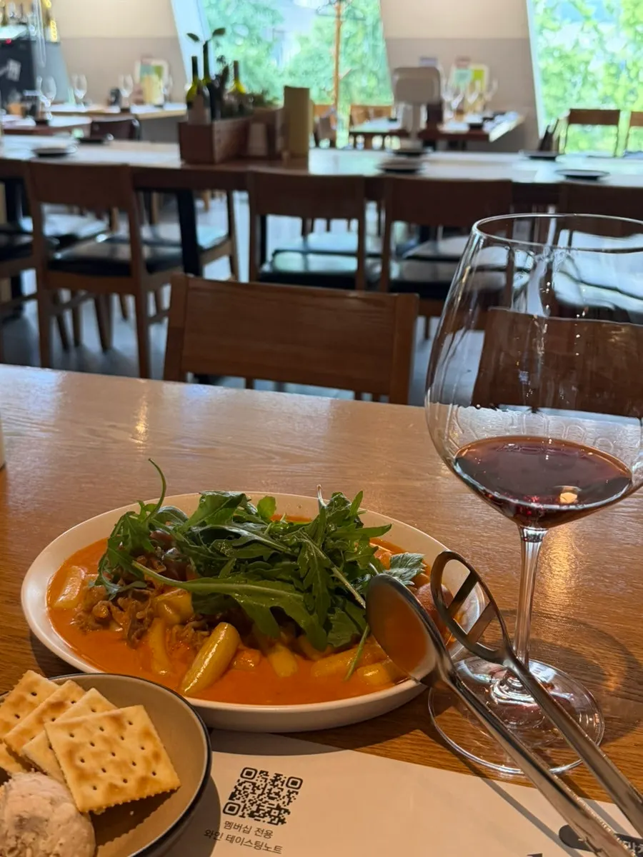 Beef belly rosé tteokbokki topped with arugula and sausage