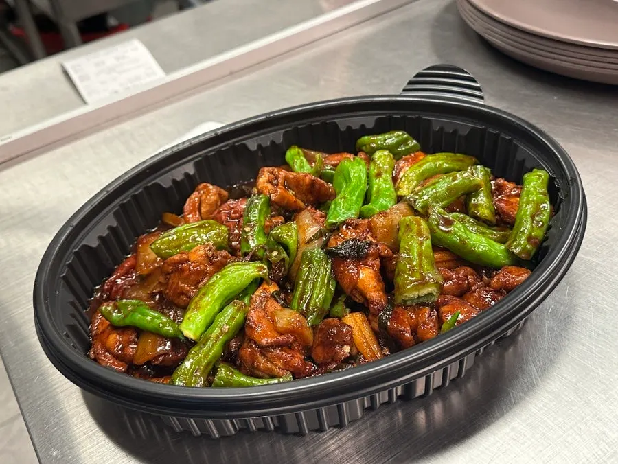 Takeout box opened to reveal boneless shishito pepper dakbokkeum