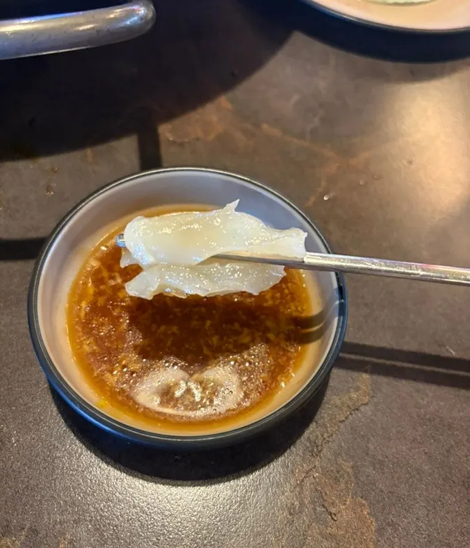 Mild hot pot broth topped with enoki mushrooms