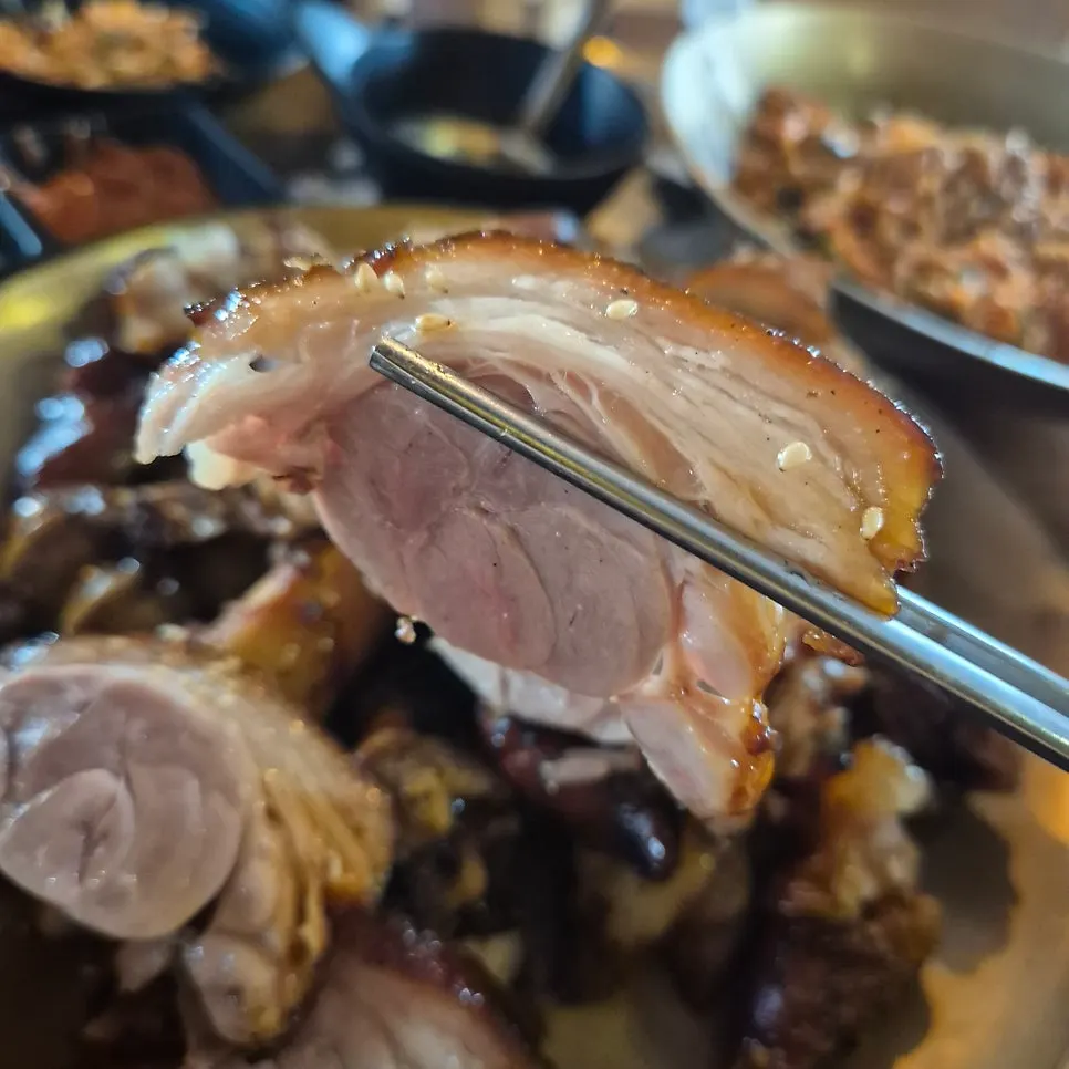 Chopsticks picking up a piece of charcoal-grilled jokbal meat