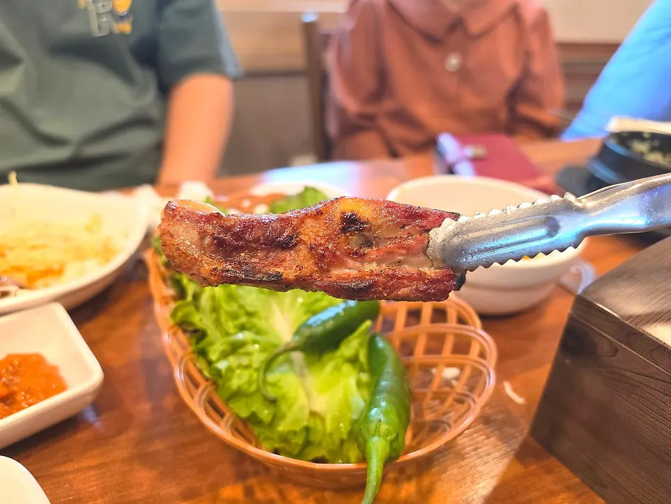 A well-cooked rib bone lifted with tongs