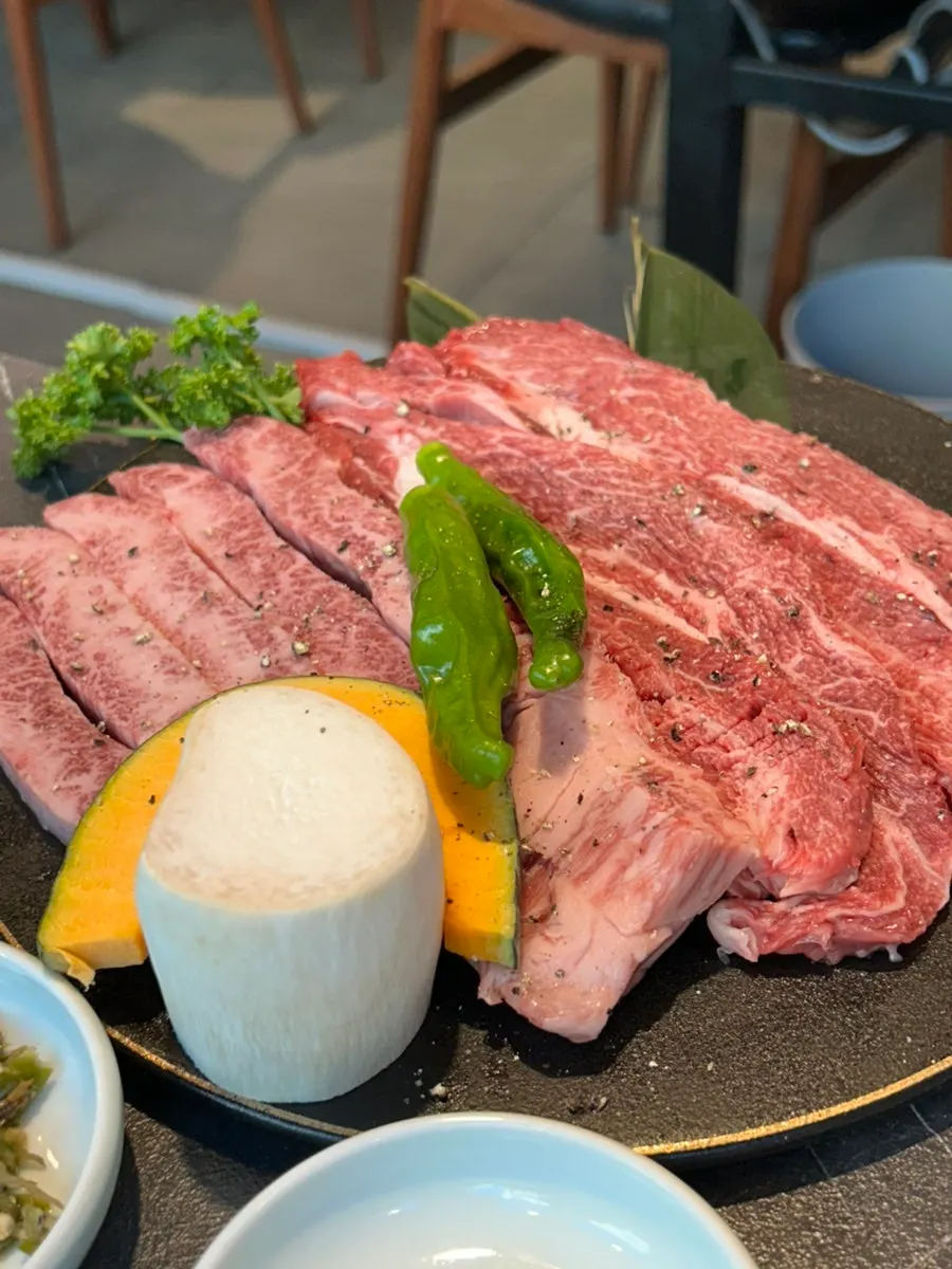 Marbled hanwoo beef set out with mushrooms, sweet pumpkin, and shishito peppers