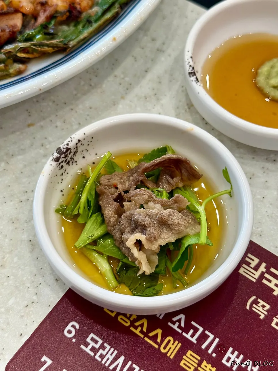 A bite of wagyu brisket shabu topped with minari