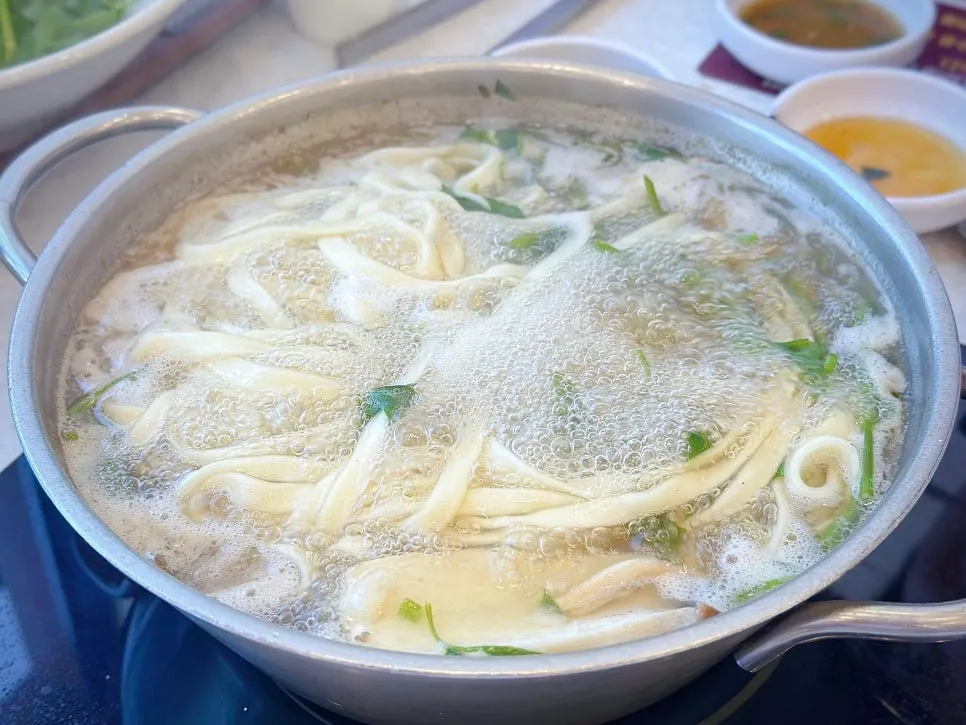 White-broth shabu kalguksu full of mushrooms and minari