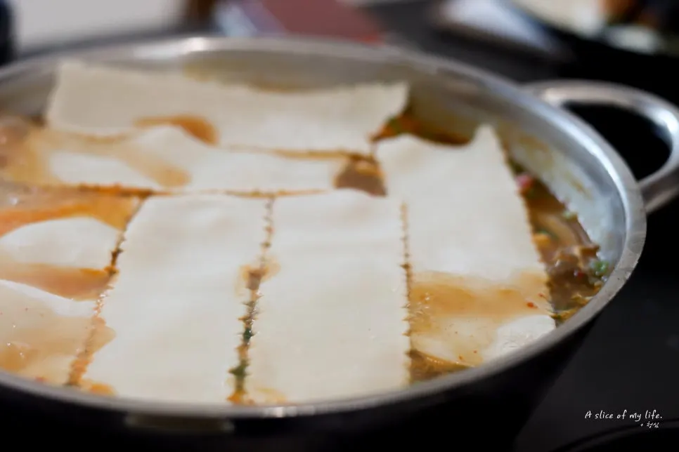 육수 위에 듬뿍 덮인 넓적한 자가제면 면