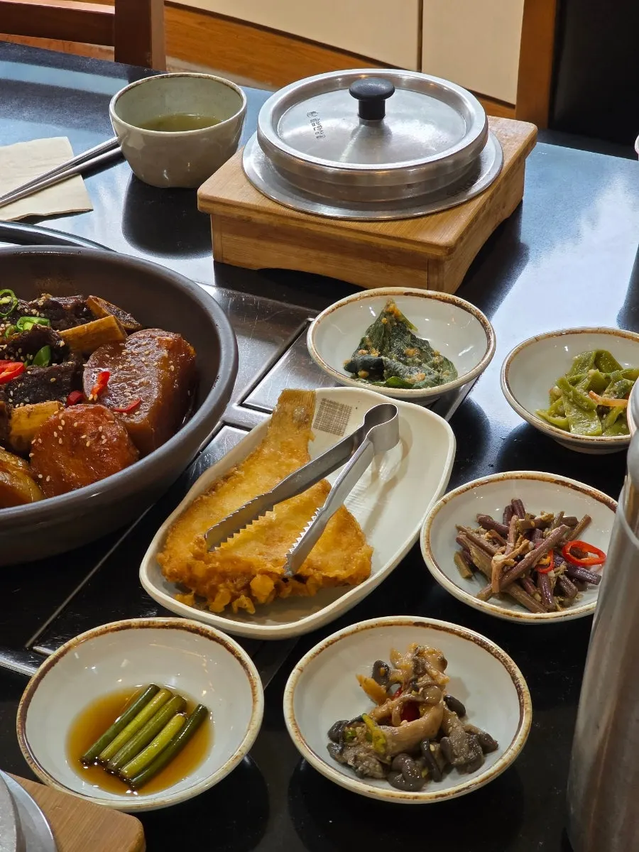 Garlic scapes, seasoned mushrooms, seasoned bracken fern, and grilled flounder banchan