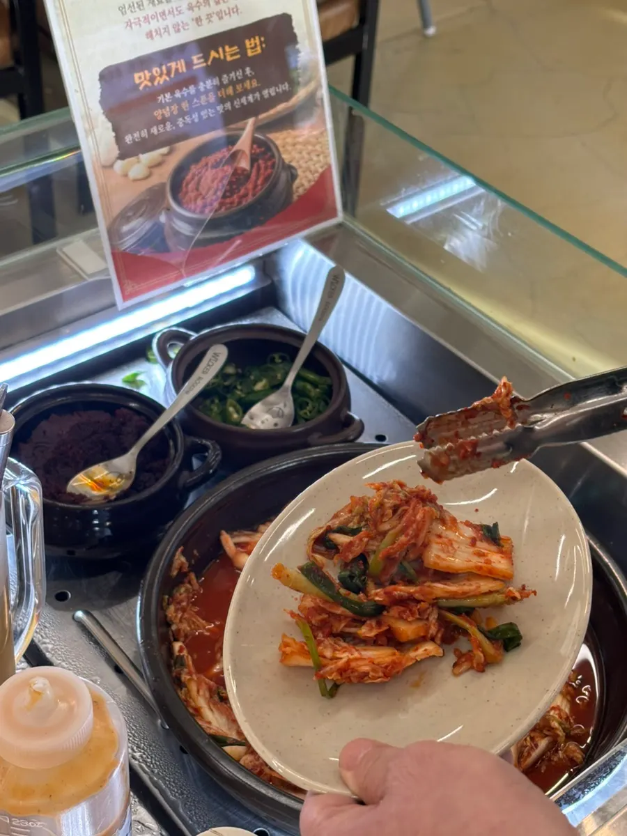 Self-service bar with broth, sauces, and kimchi