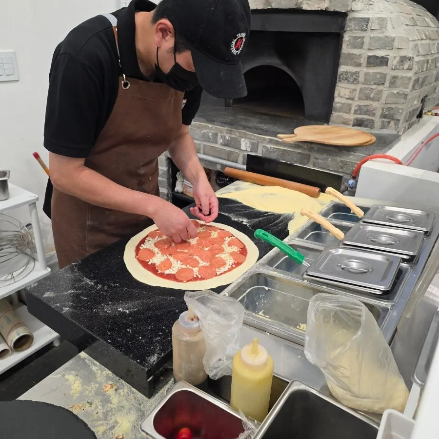 Toppings being placed on pizza dough
