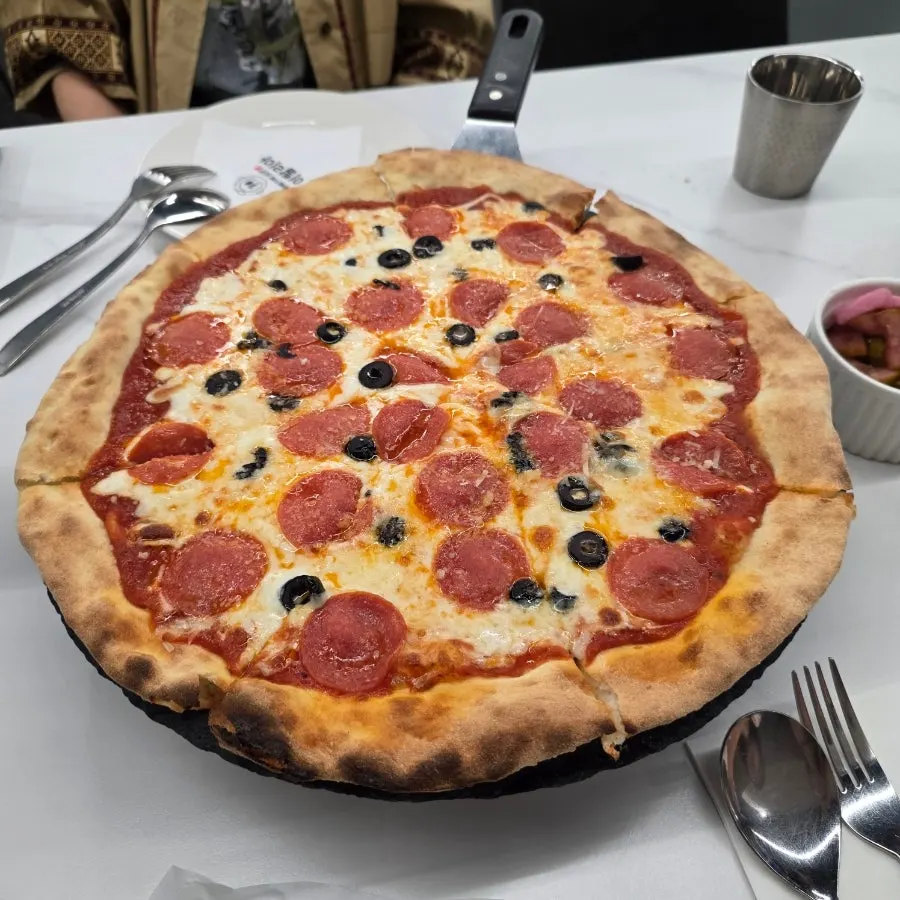 Whole pizza topped with pepperoni and olives