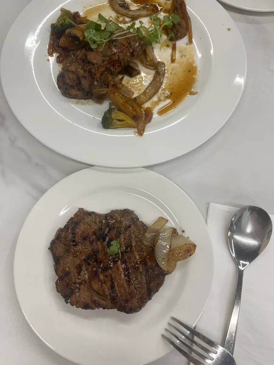 Table spread of pork neck steak and risotto ordered by two people