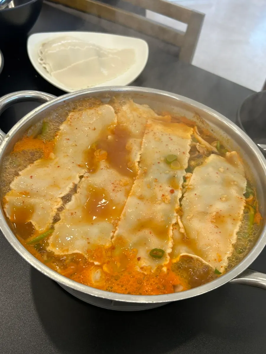A staff member adding flat kalguksu