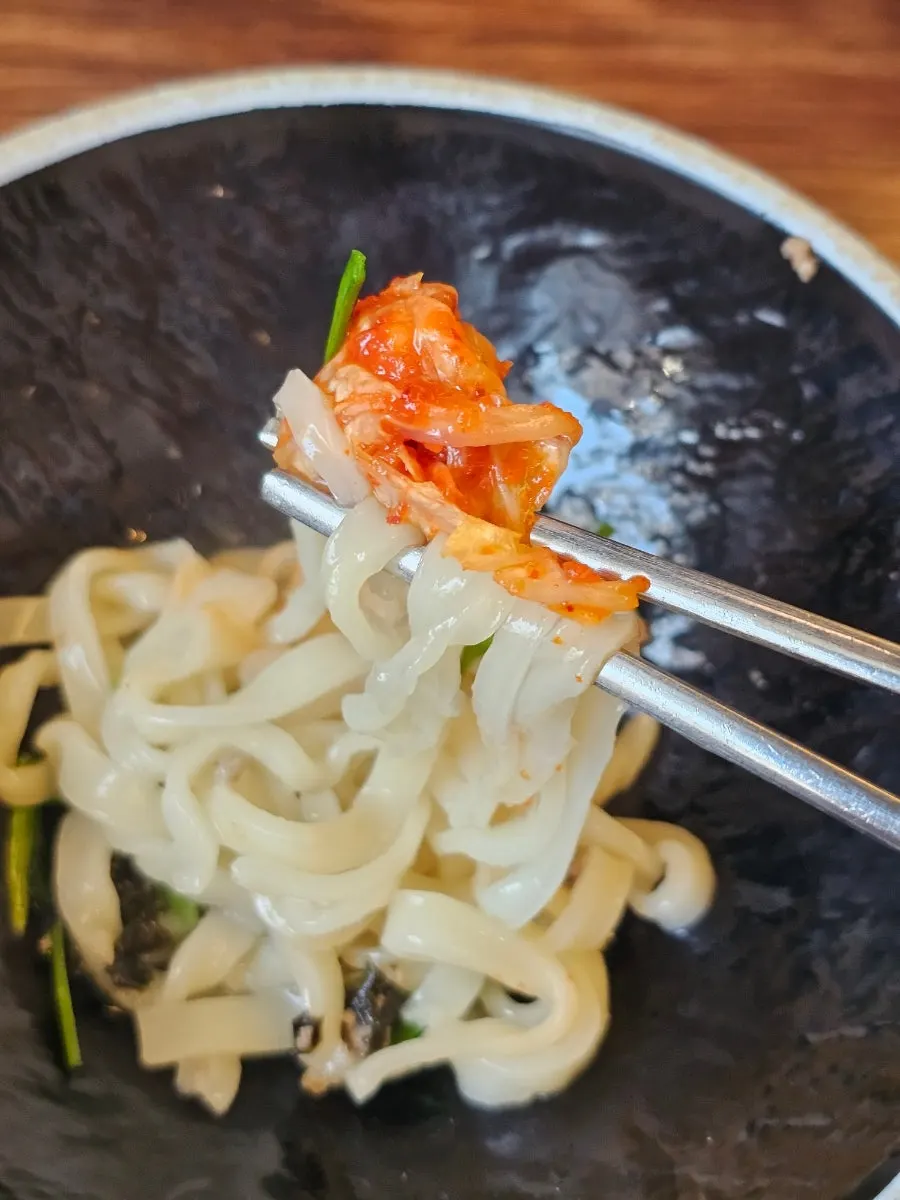 Kalguksu noodles topped with kimchi