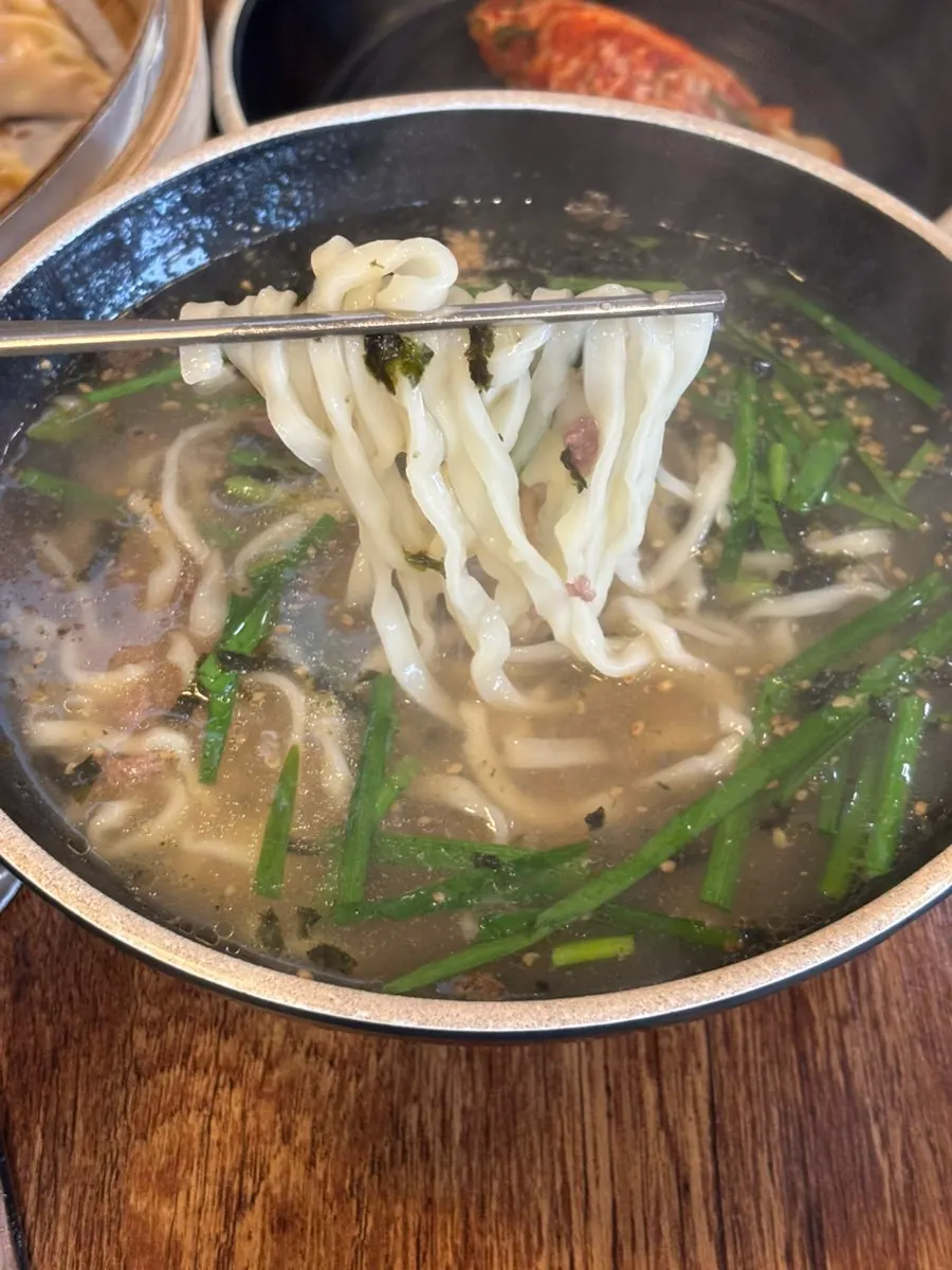 A large steamed kimchi dumpling with the filling visible