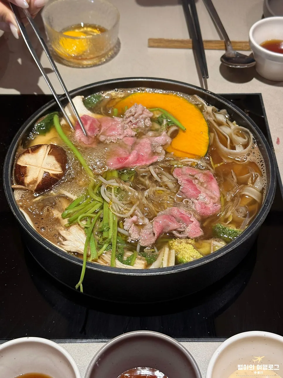 だしで野菜と肉を煮る様子