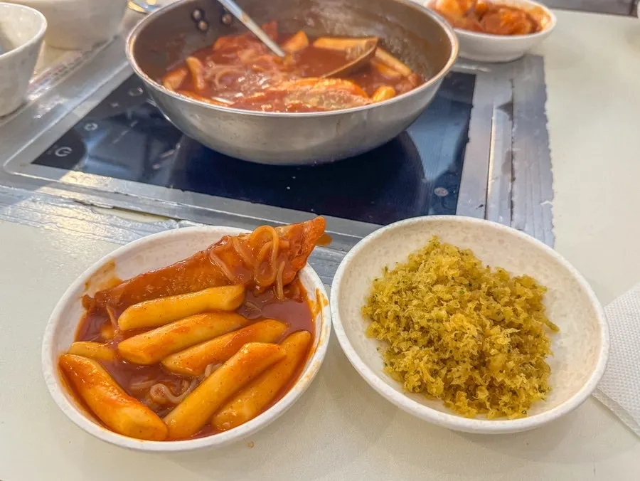 Mandu dunked into the broth of the instant tteokbokki