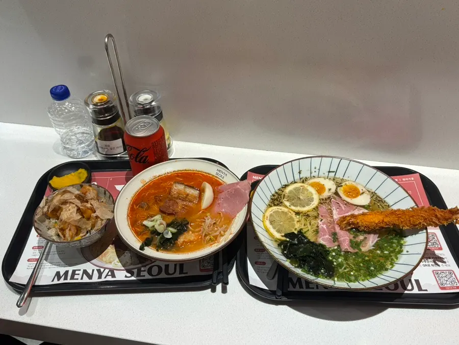 Two bowls of ramen and a side dish at the bar seat