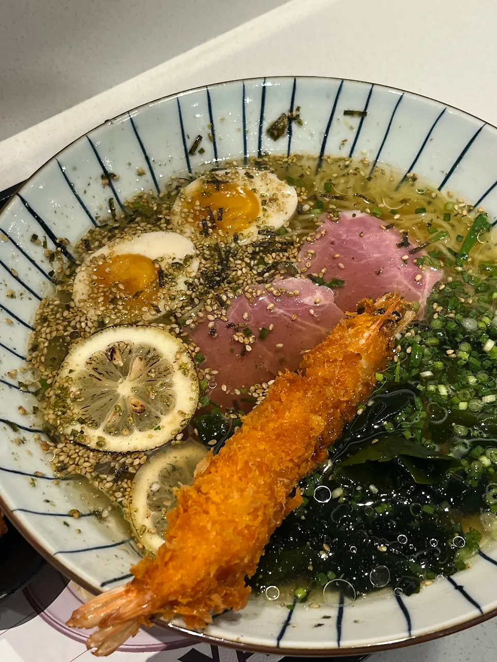 Giant prawn cold ramen topped with fried shrimp, soft-boiled egg, and lemon