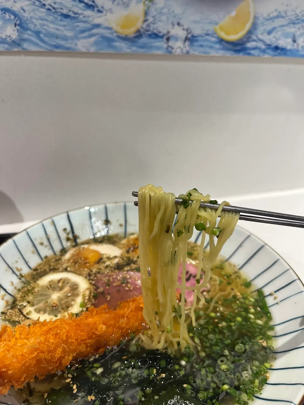 A chopstick-full of thin, capellini-like cold ramen noodles
