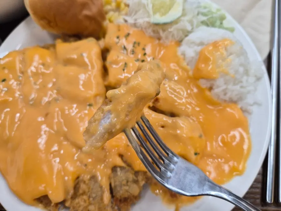 A piece of cheddar cheese cutlet picked up with chopsticks