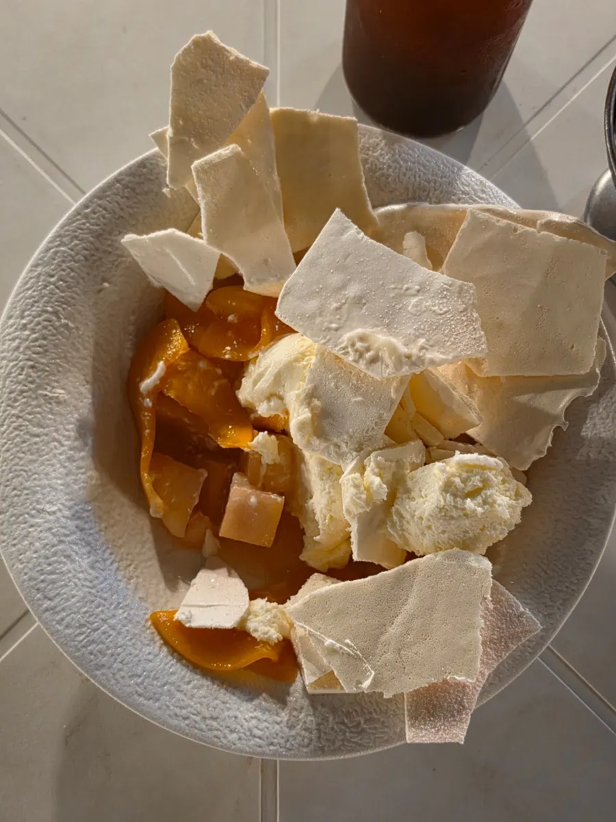 Cracked-open pavlova revealing peach and yogurt cream inside