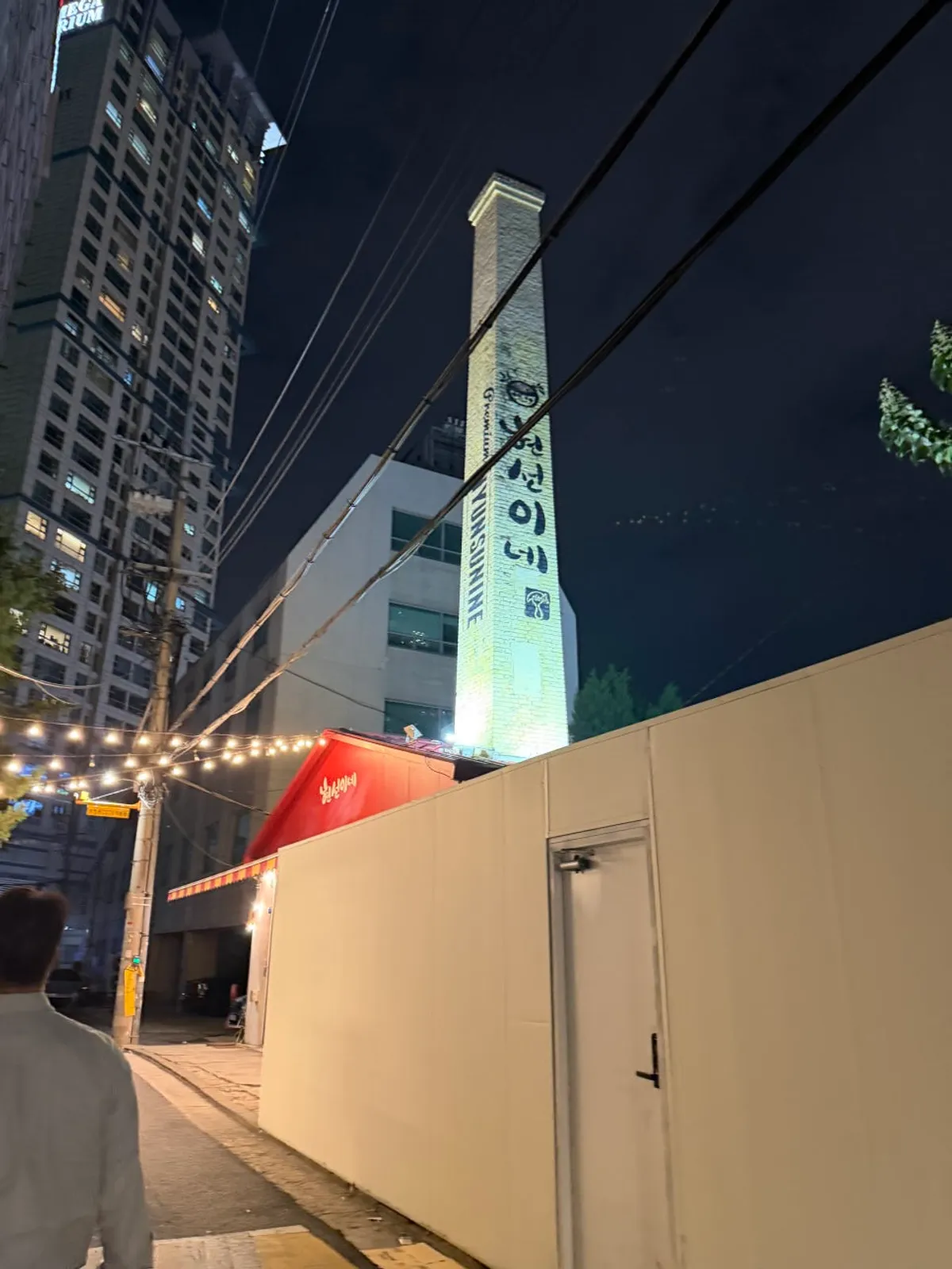 Red sign of Hyeonseonine Yongsan Main Branch at the end of a light bulb-lit alley