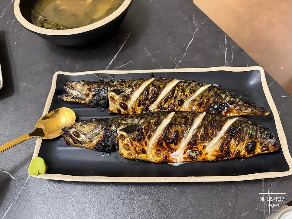Large grilled mackerel compared in size to a spoon