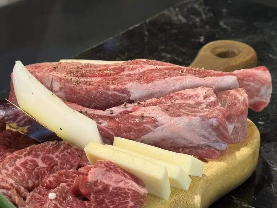 Meat and side ingredients cooking over charcoal