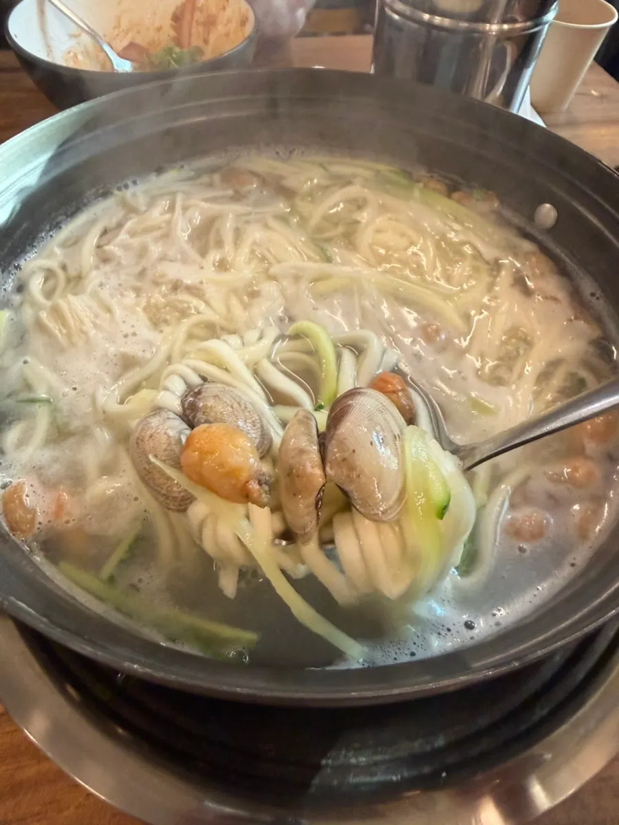 Pot of kalguksu simmering with seafood in pufferfish broth