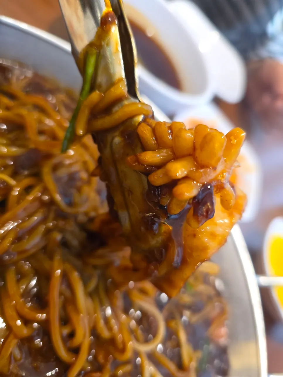 Noodles and squid lifted with tongs from the tray jjajang