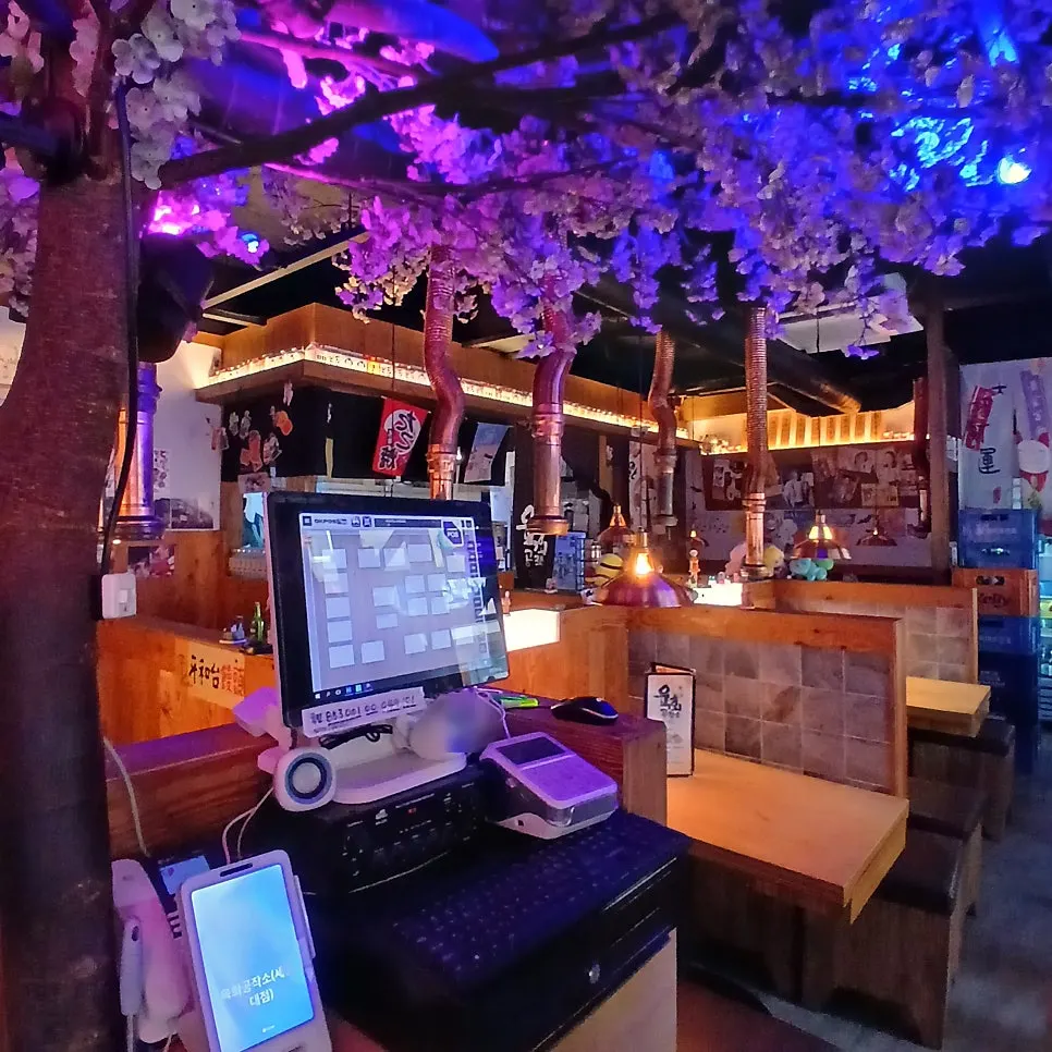 Bar interior with a cherry blossom tree sculpture and purple lighting