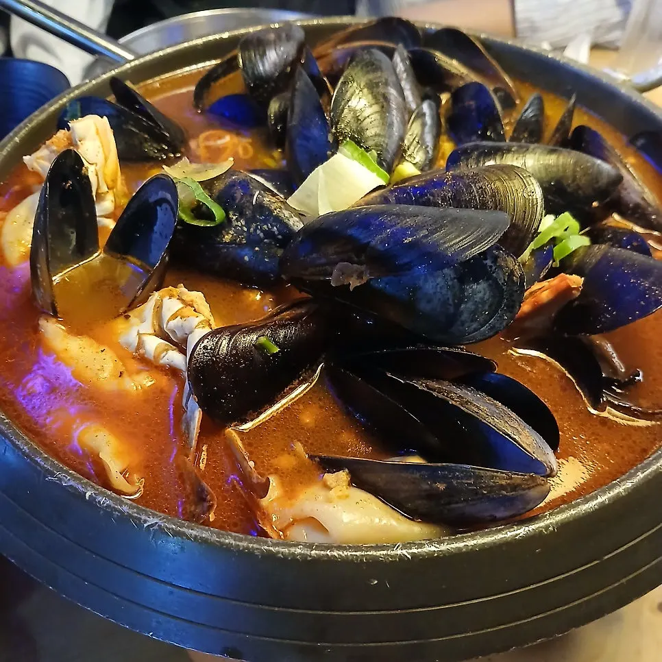 A pot of seafood jjamppong tang piled with mussels