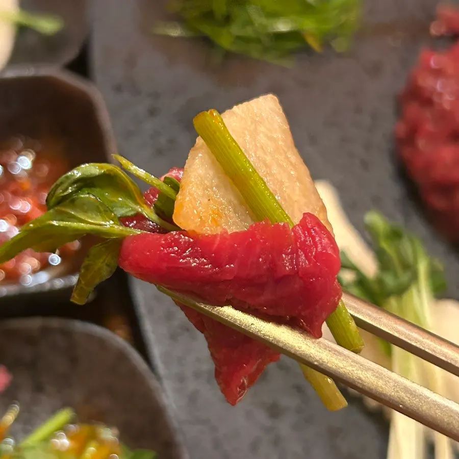 A wrap of seaweed, beef sashimi, pear, and cheese