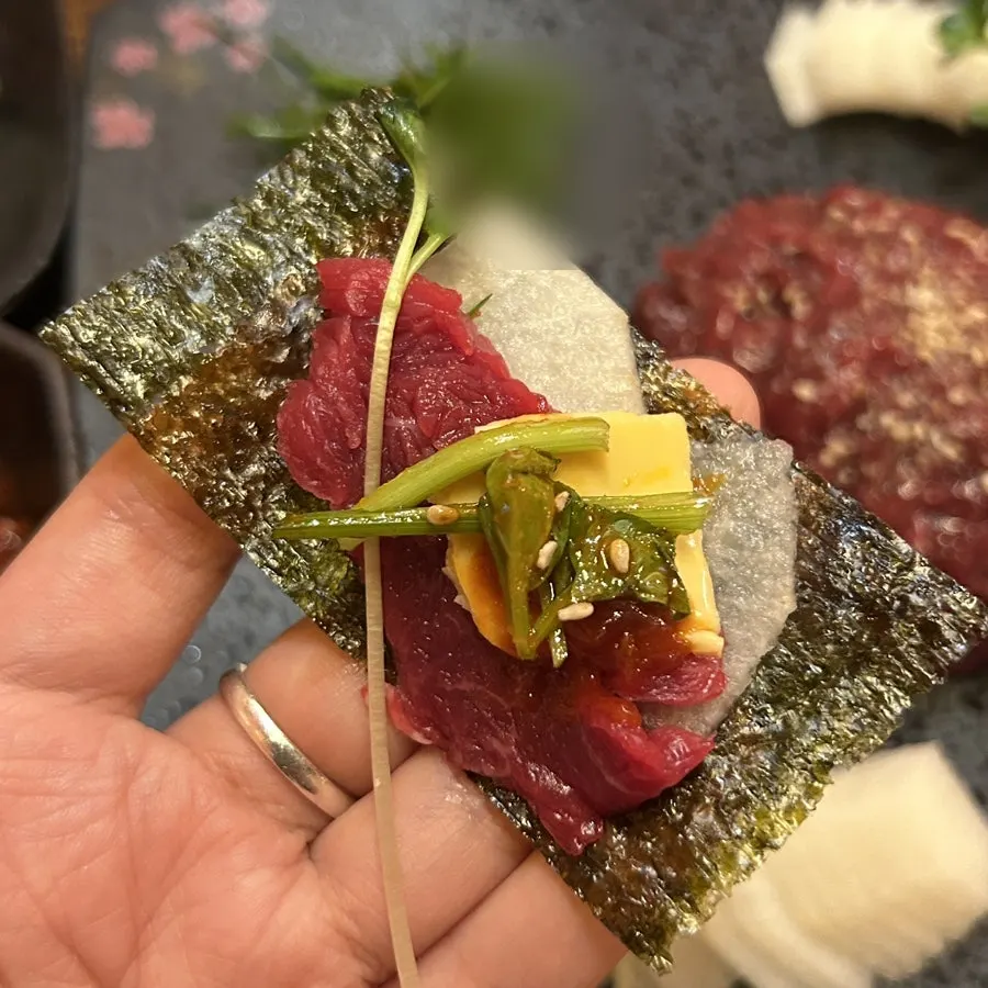 Lifting up a bite of the beef sashimi wrap