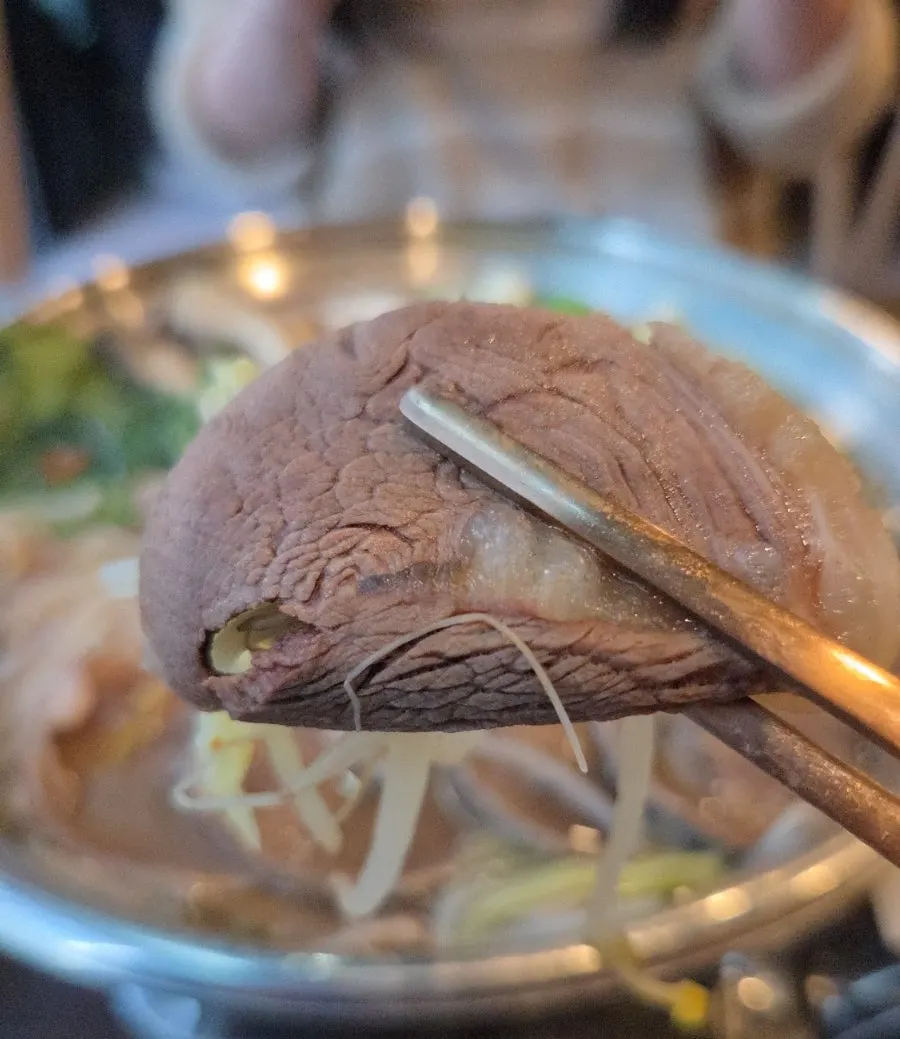 用夾子夾起的一塊水煮肉
