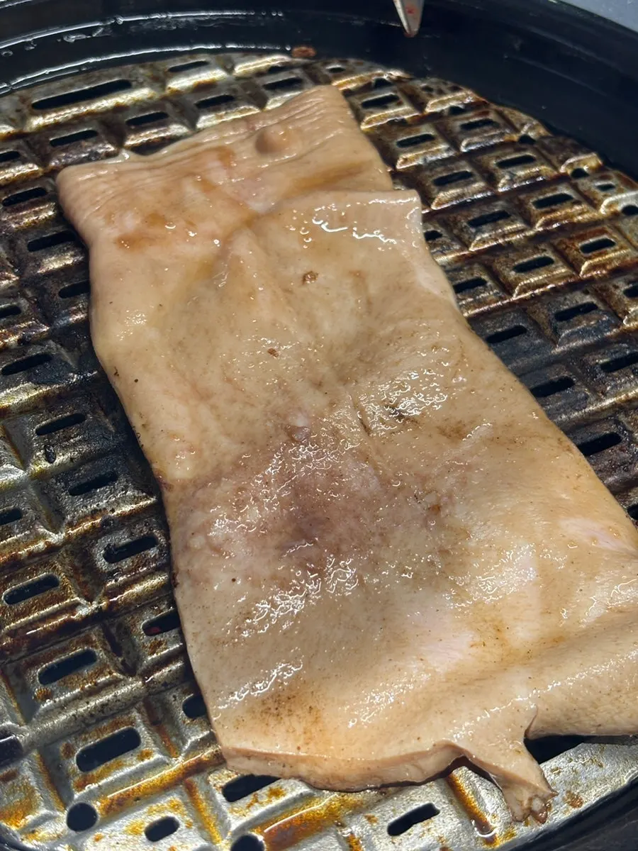 Yukjjip's patented tightly-holed grill plate with grilled garlic