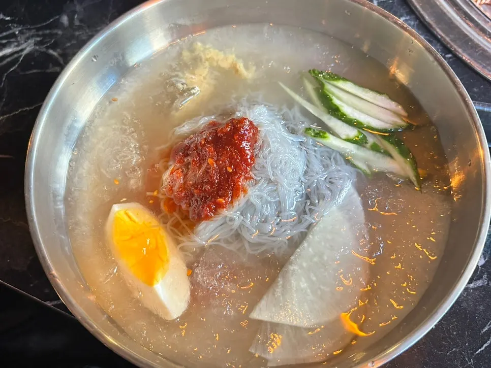 A bite of thin mul naengmyeon noodles